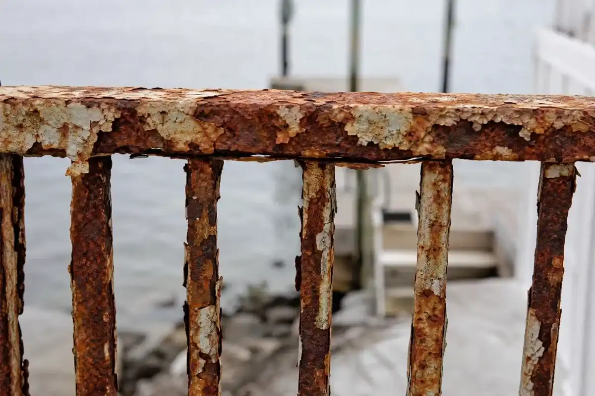 Rusted waterfront railing before powder coating, corrosion across the top rail and balusters